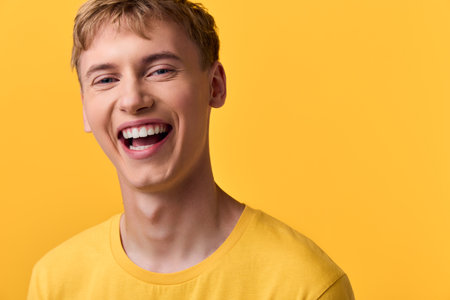 Smile, young man in a yellow tee against a bright yellow background, showcasing cheerful emotion and casual style for lifestyle, advertising and positive impact creative conceptsの写真素材