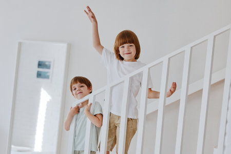 Two cheerful boys playfully climbing stairs in a modern home, smiling and enjoying their time together. Bright and inviting atmosphere enhances their joy.の写真素材