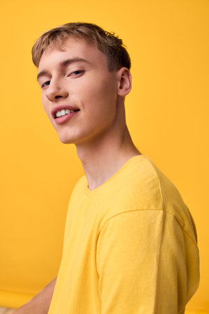 Close up of a smiling man in a yellow t shirt against a bright yellow backdrop, casual studio setting with a relaxed pose, vibrant color and contemporary moodの写真素材