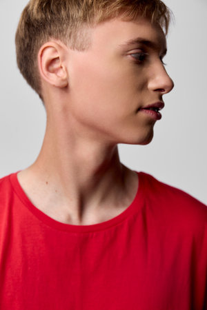 Profile view of a young boy in a red shirt, calm expression, clean studio lighting, neutral...