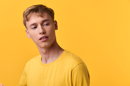 Yellow color palette with a young man in a yellow shirt against a matching backdrop, casual fashion look, studio lighting, modern and clean style for stock imageryの写真素材