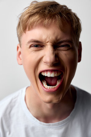 Scream, shouting, anger, expression, close up, male, youth, energy, emotion, mouth open in a loud yell, capturing raw intensity, dynamic facial moment, bold mood for urgency, drama or expressiveの写真素材