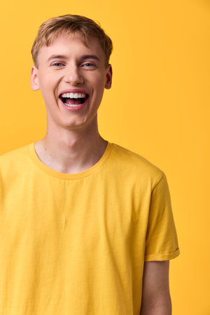 Smiling male in a bright yellow t shirt against a solid yellow backdrop, conveying energetic happiness, casual fashion and cheerful mood for lifestyle stockの写真素材