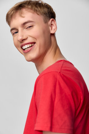 Smiling young male in a red shirt, casual and cheerful, closeup shot capturing a warm expression, bright lighting and optimistic mood suitable for lifestyle or fashion stockの写真素材