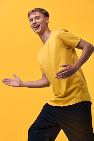 Joy, happiness, movement, and energy burst as a cheerful youth in a yellow shirt laughs mid motion against a bright yellow background, conveying fun and vitality, perfect for advertising, lifestyle,の写真素材