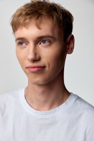 Young man with calm expression in a studio shot, wearing a casual white shirt, closeup framing, soft lighting and clean minimalist mood for lifestyle or fashion projectsの写真素材