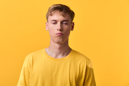Pouty expression on a man wearing a yellow shirt against a bright background, studio shot with bold...