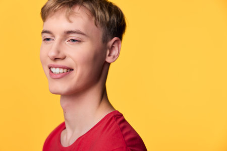 Smiling man in a red shirt against a bright yellow background, showcasing warmth and approachability for lifestyle, close up, positive mood, vibrant colors, friendly energyの写真素材
