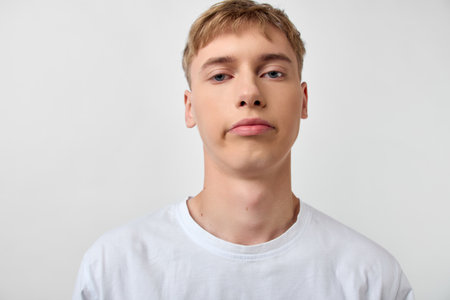 Young man headshots, white t shirt, studio, neutral expression, close up, plain background, minimal, casual, facial lighting, shot of model, warm hue.の写真素材