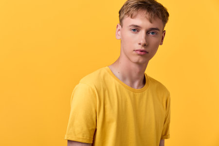 Yellow shirted man stands against a bright yellow backdrop in a casual studio shot, showcasing clean lines, minimal style and contemporary fashion appealの写真素材
