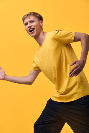 Energetic youth dancing in a bright yellow backdrop, showcasing dynamic movement, laughter and casual fashion in a lively studio vibeの写真素材