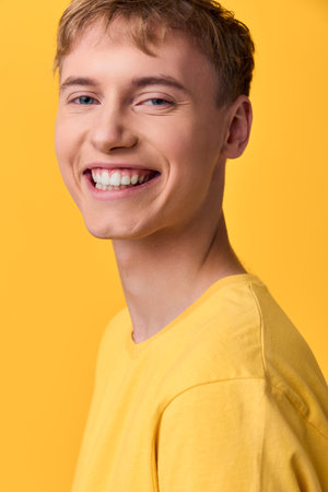 Smiling man in a yellow shirt against a vibrant yellow background, warm studio lighting highlights friendly expression and casual style, suitable for lifestyle or fashion branding and advertisementsの写真素材