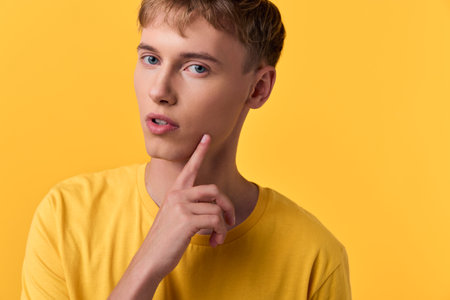 Thinking, contemplation and a pensive expression in a closeup of a young male in a yellow shirt,...