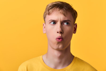 Surprised man wearing a yellow shirt against a yellow backdrop, capturing a moment of astonishment...