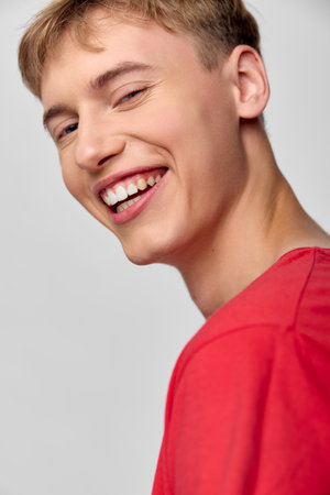 Close up of a smiling man in a red shirt, warm expression and bright eyes, casual head and shoulders...
