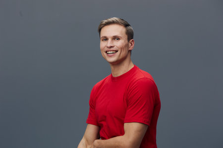 Smiling man wearing red t-shirt looking happy cheerful confident pose studio portrait blue background. People lifestyle conceptの写真素材