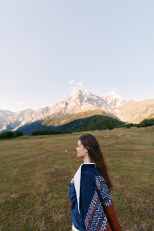 woman profile walking in meadow with mountains in background, landscape view of nature outdoors,...