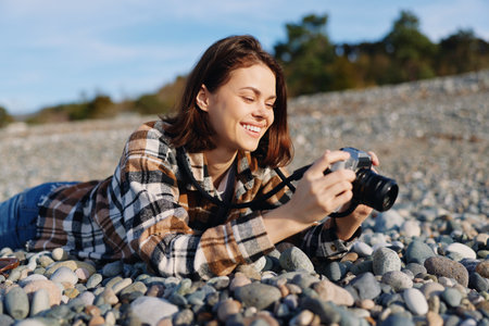 Photographer lying on a pebble beach with a camera, capturing outdoor moments in natural light....