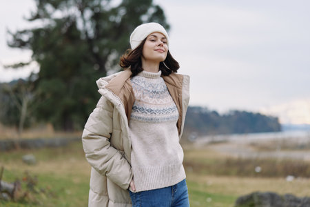 Winter outdoors, woman wearing a warm coat and knitted sweater, beanie, posing confidently in an...