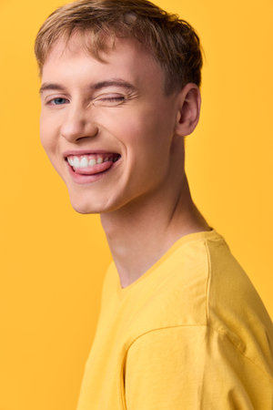 Close up of a cheerful, casual figure with a bright yellow shirt, a playful wink and warm smile,...