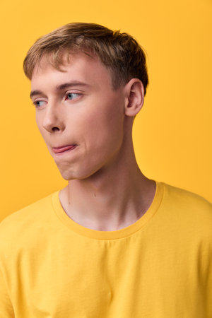 Young man, yellow shirt, casual lifestyle, studio background, fashion expression, thoughtful gaze, bright warm tones, clean composition, minimal props, suitable for lifestyle, fashion, editorial useの写真素材