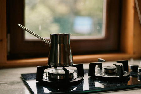 Kettle on a gas stove in a kitchen with metal cookware and active burners, portraying a practical...