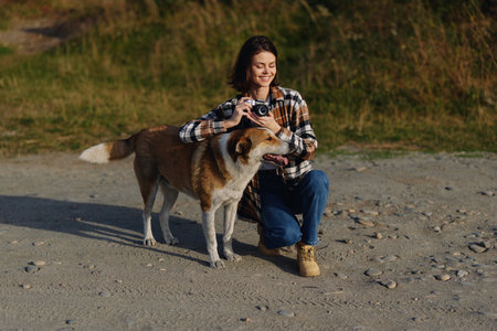 Dog and woman on a sandy beach, outdoor photography moment as she holds a camera and smiles,...