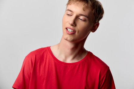 Man, relaxed mood with closed eyes wearing a red shirt in a simple studio setting, conveying calm, casual style and comfort for lifestyle, wellness and everyday momentsの写真素材