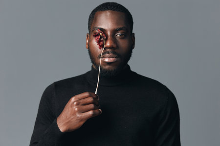 Black man with dark skin holding dried flower in front of eye in creative visual designer style....