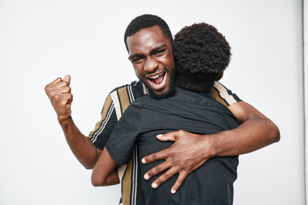 African American man with dark skin celebrating and hugging child with curly hair in casual clothes on white background for family and happiness.の写真素材