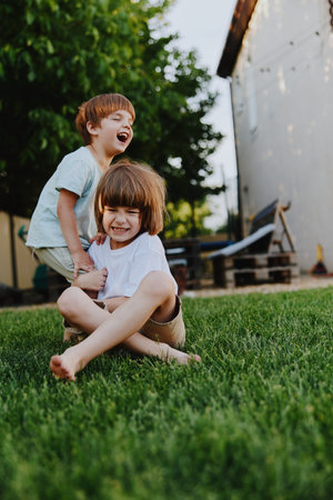 Happy children playing outdoors, enjoying a sunny day surrounded by greenery, creating joyful memories in a vibrant backyard environment.の写真素材