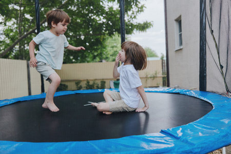 Happy children playing together on a trampoline, enjoying their time outdoors with laughter and joy under the sunny sky, showcasing carefree youth and playfulness.の写真素材