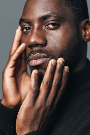 African man with dark skin and short hair touching face in creative conceptual visual style. Closeup...