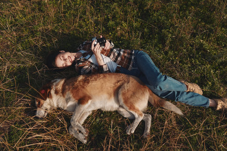 Person lying on grass outdoors with a dog, relaxed and in a peaceful moment, enjoying nature and...