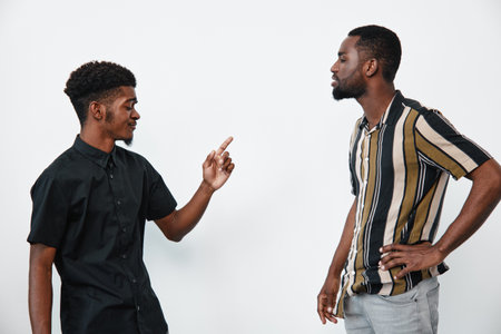 Two black men with dark skin having a serious conversation in casual clothes on white background....