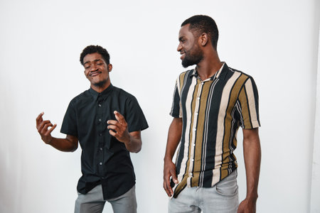 Two young African American men with dark skin standing and smiling together in casual clothes on...