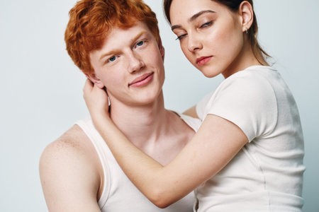 Young couple with red hair man and woman embracing, closeup portrait with white shirts on plain background, relationship, affection, love and intimacy with skin details.の写真素材