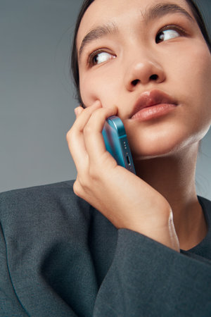 Young woman talking on smartphone with thoughtful expression, closeup of face and hand holding...