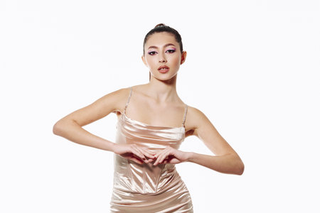 Stylish young woman poses confidently wearing silky slip dress. Her hair is tied back and makeup is creative with pink and purple stylish tones.の写真素材