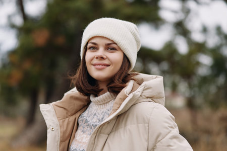 Winter, woman portrait outdoors in a warm coat and beanie, soft natural light, relaxed smile, autumn...