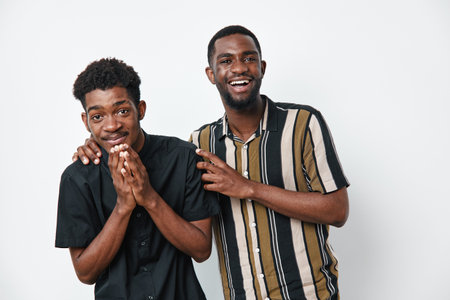 Two young African American men with dark skin smiling and laughing together in casual clothes on white background. Friendship, happiness and positive emotions.の写真素材