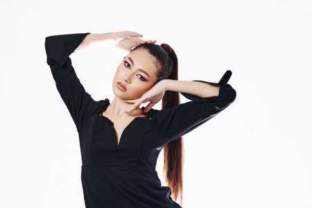 Fashion model with dramatic makeup poses gracefully in an elegant black top against a white background. Concepts include beauty, fashion, creative expression, and modern style.の写真素材