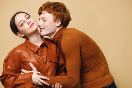 Couple, woman and man embracing in casual autumn clothing with warm brown tones. Young lovers showing affection and closeness in studio, lifestyle portrait with soft light.の写真素材