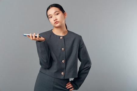 Young businesswoman in formal suit holding smartphone with hand raised and confident gesture...