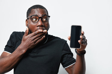 African American man with dark skin and glasses showing smartphone with blank screen and covering...