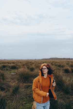Woman lifestyle concept with a young woman wearing an orange jacket and sweater standing in a...