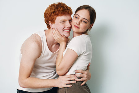 Young couple embracing with woman holding mans face tenderly and man smiling for love, affection,...