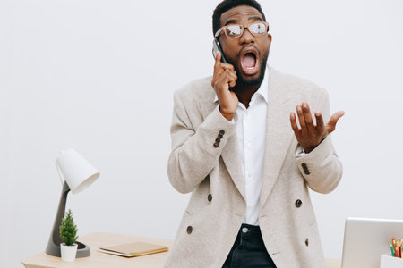 Young professional man with glasses in a beige blazer talking on mobile phone while showing...