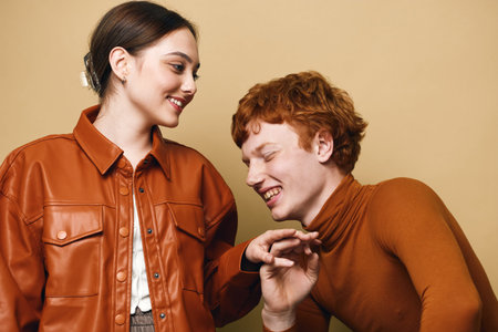 Young woman and man smiling and laughing interacting in casual autumn clothing with warm tones on...