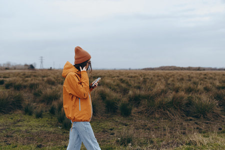 Woman lifestyle concept with a young woman wearing an orange jacket and hat walking outdoors in a...